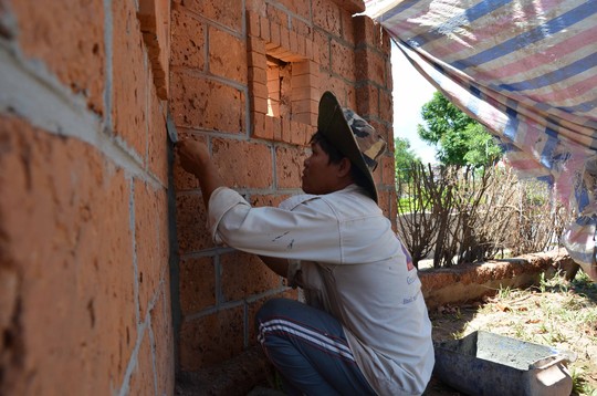 Thợ xây đang tô lại bức tường bọc bên ngo� i khu lưu niệm xây bằng đá tổ ong